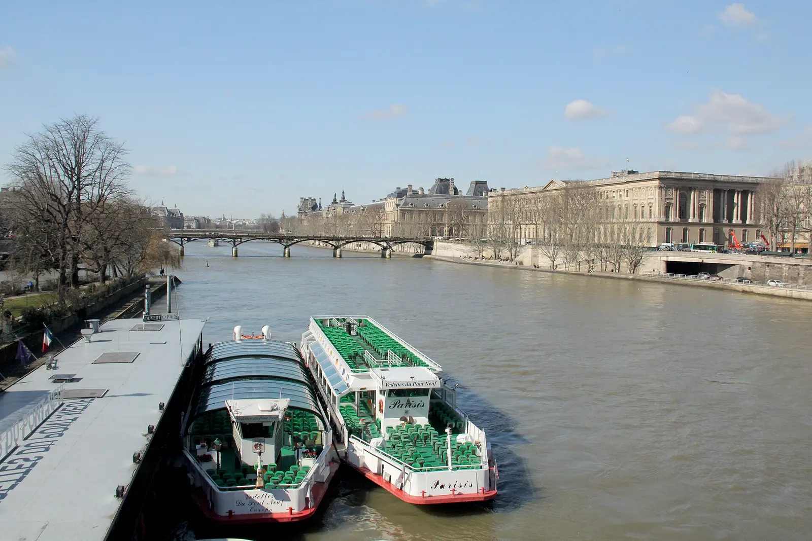 Vedettes du Pont Neuf boats moored at their pier, with the Seine and the Louvre beyond